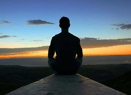 Silhouette of person seated watching sunset 