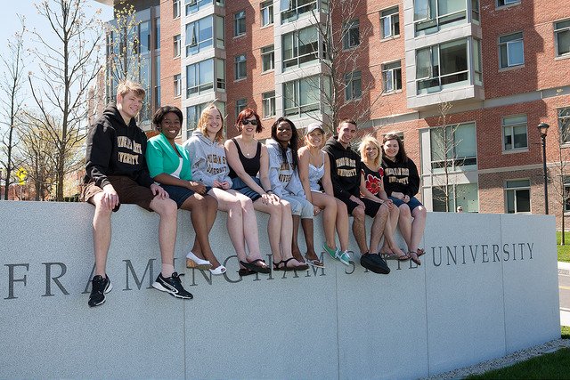 Group of students sitting on a wall that reads "Framingham State University"