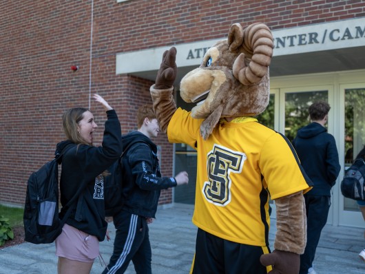 Sam the Ram high-fiving a student