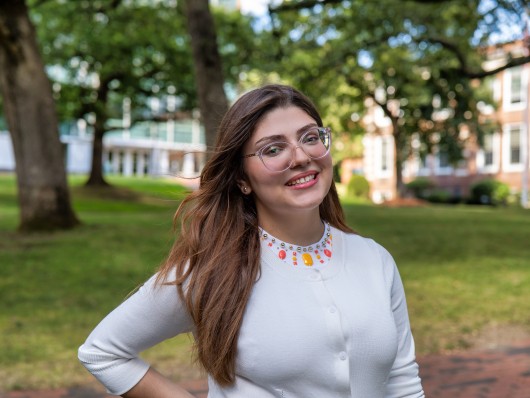 Photo of Ana Julia standing in front of trees and buildings at Framingham State University