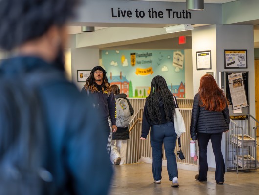 Students walking in the McCarthy Center under a "Live to the Truth" sign