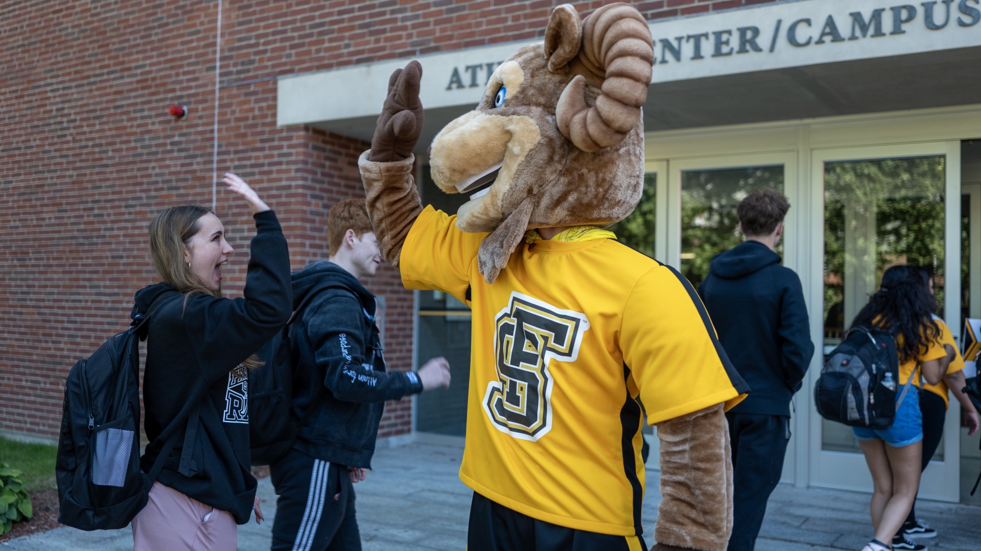 Sam the Ram high-fiving a student
