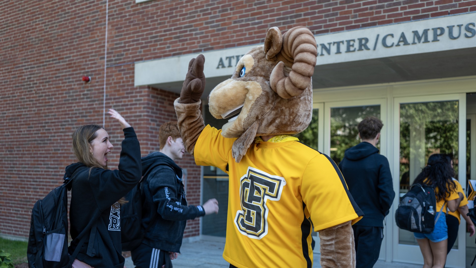 Sam the Ram high-fiving a student