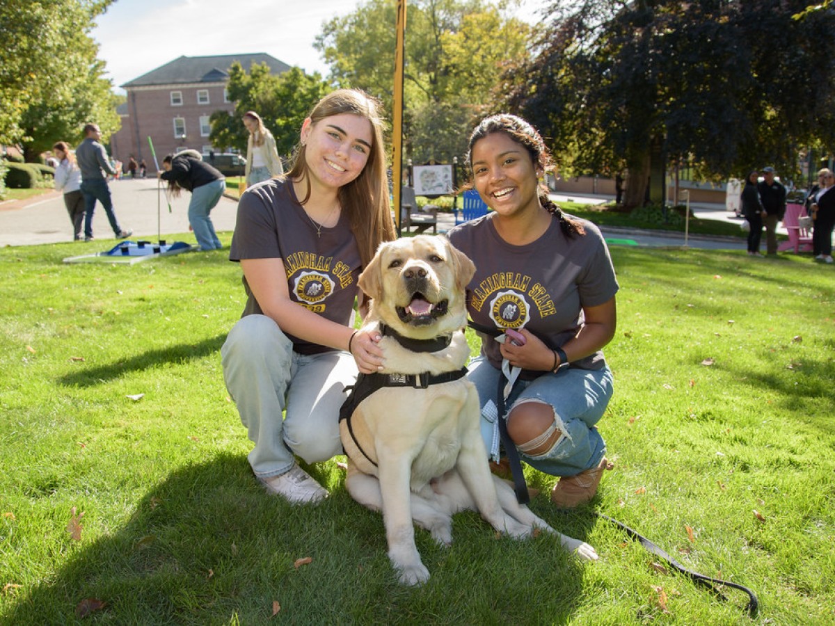 Two students with Ramsey, FSU's comfort canine