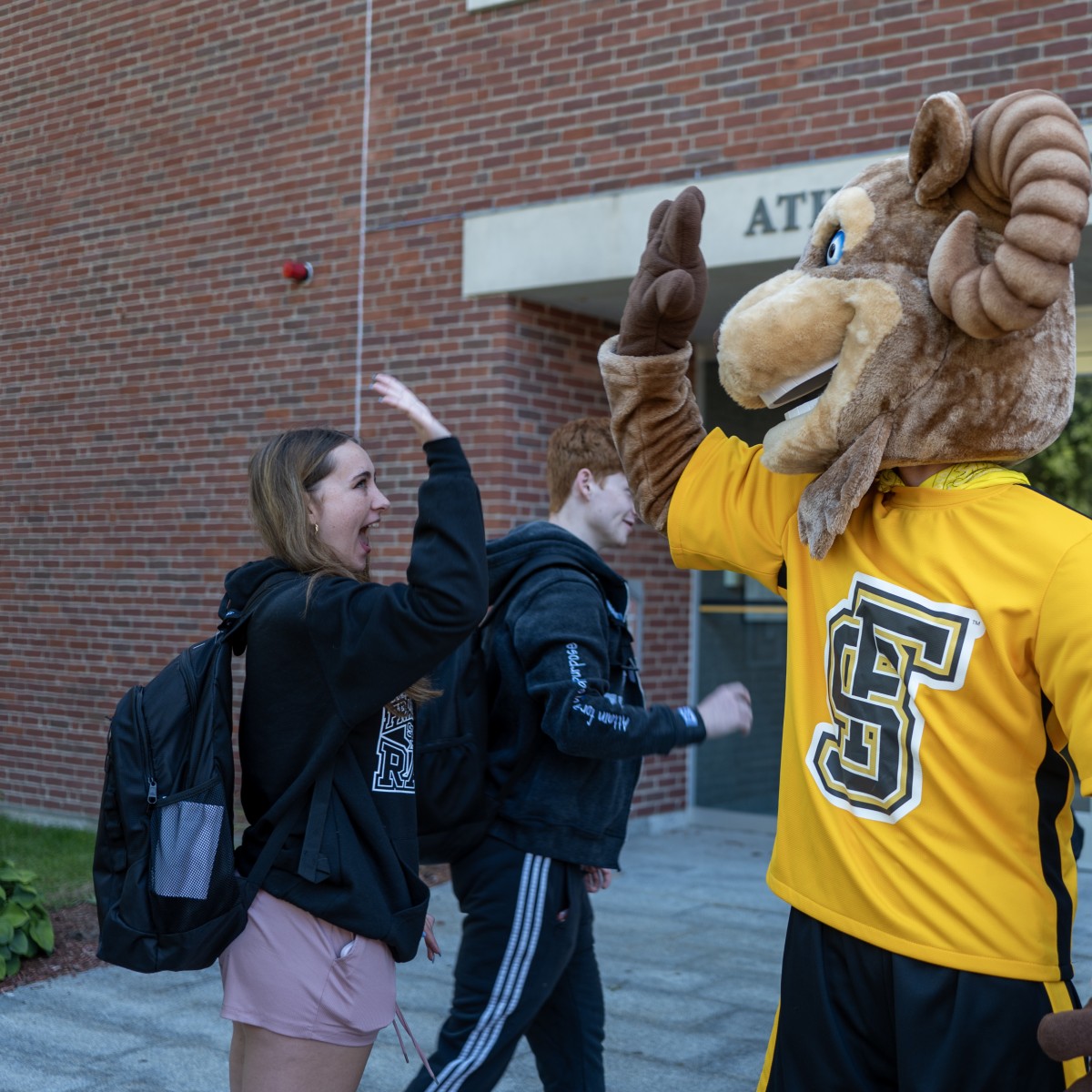 Sam the Ram high-fiving a student