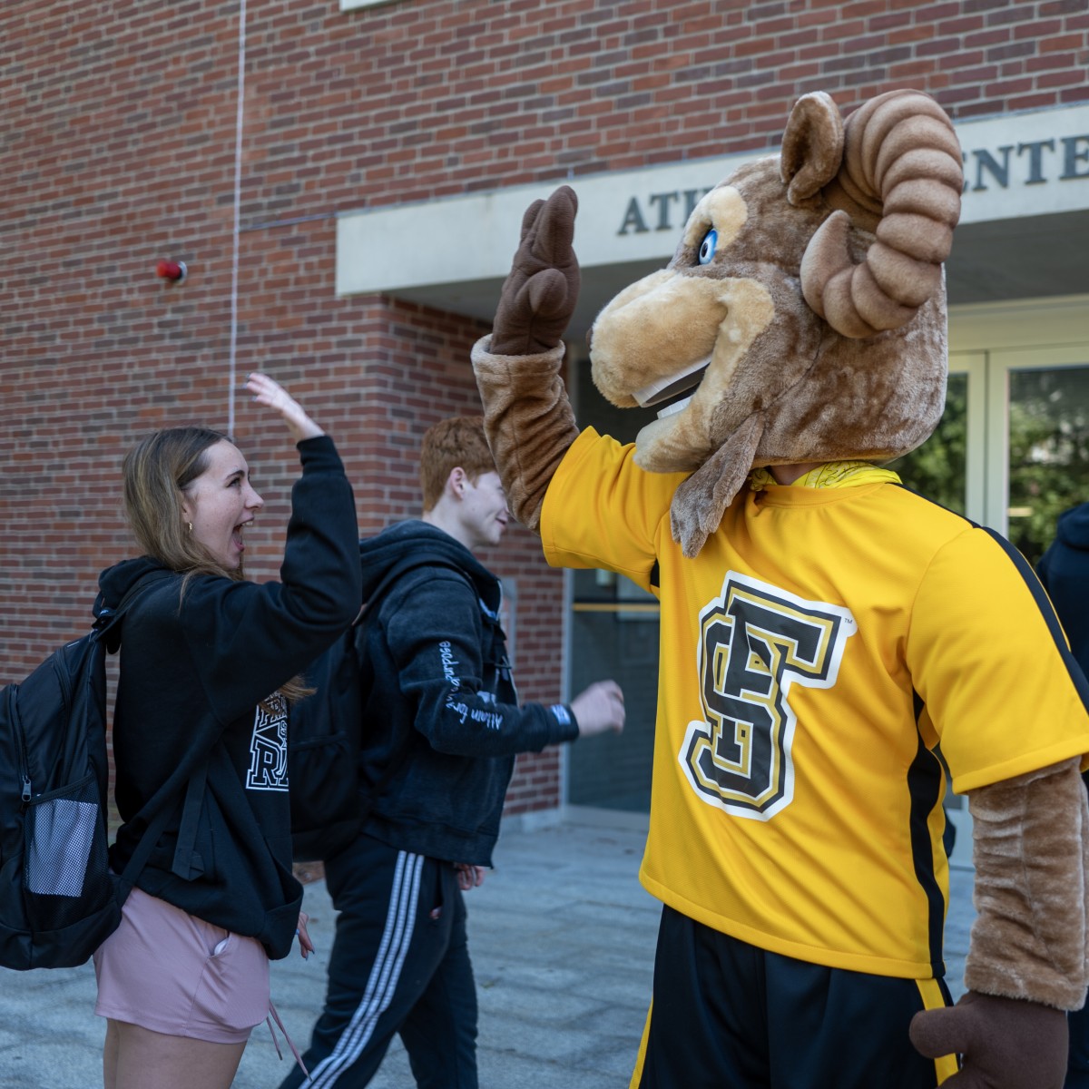 A student giving the Ram Mascot a high five