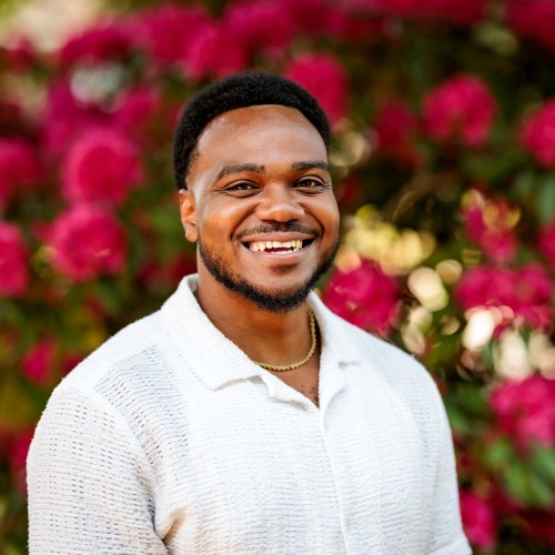 Photo of a man smiling in front of flowers